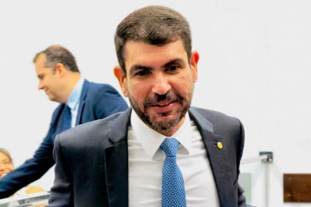 Político Marangoni de terno e gravata azul sorrindo em evento.