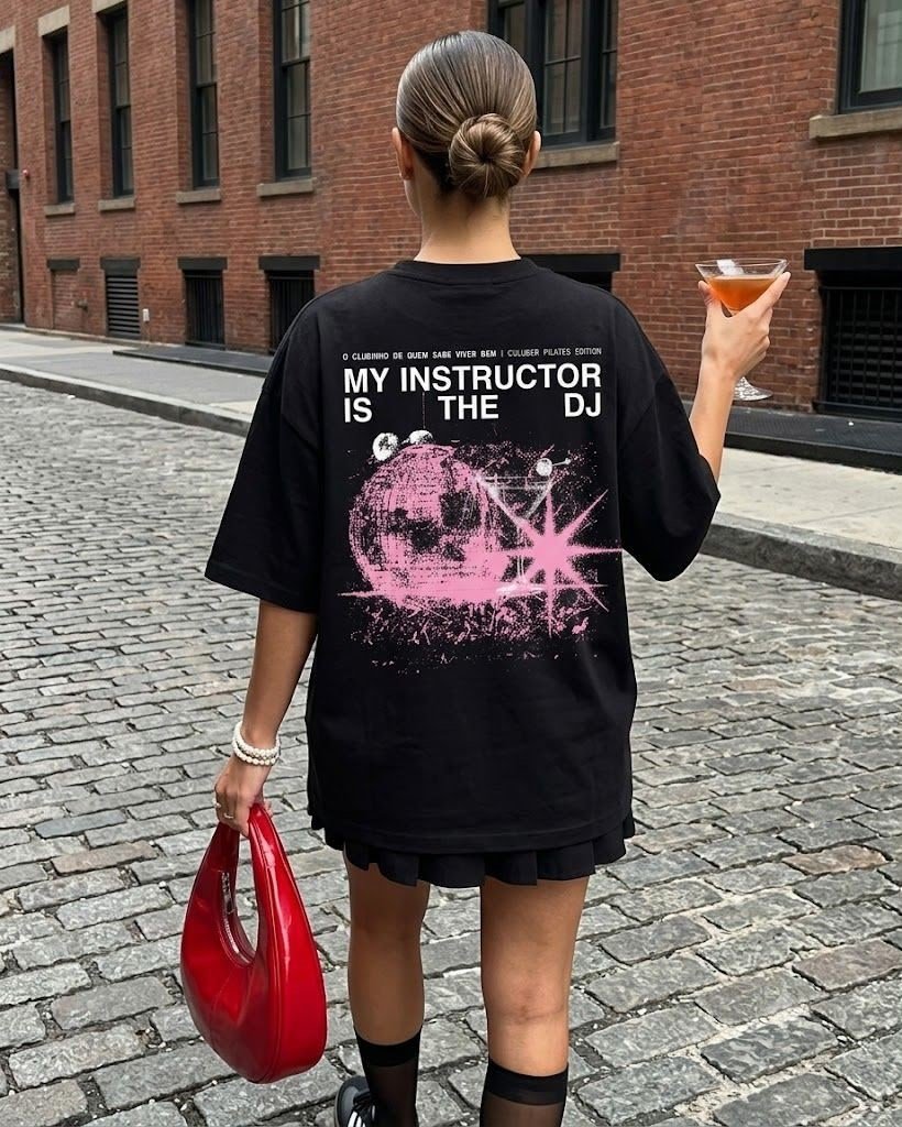 Mulher de costas usando camiseta preta com estampa gráfica rosa.