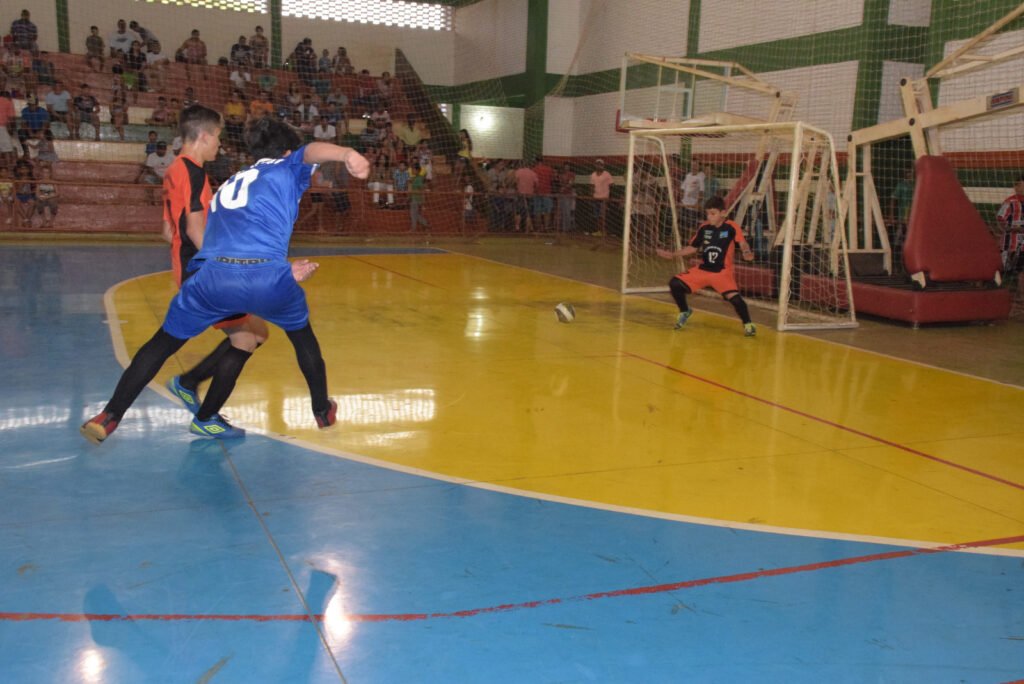 Jogador de futsal chutando a bola em direção ao gol.
