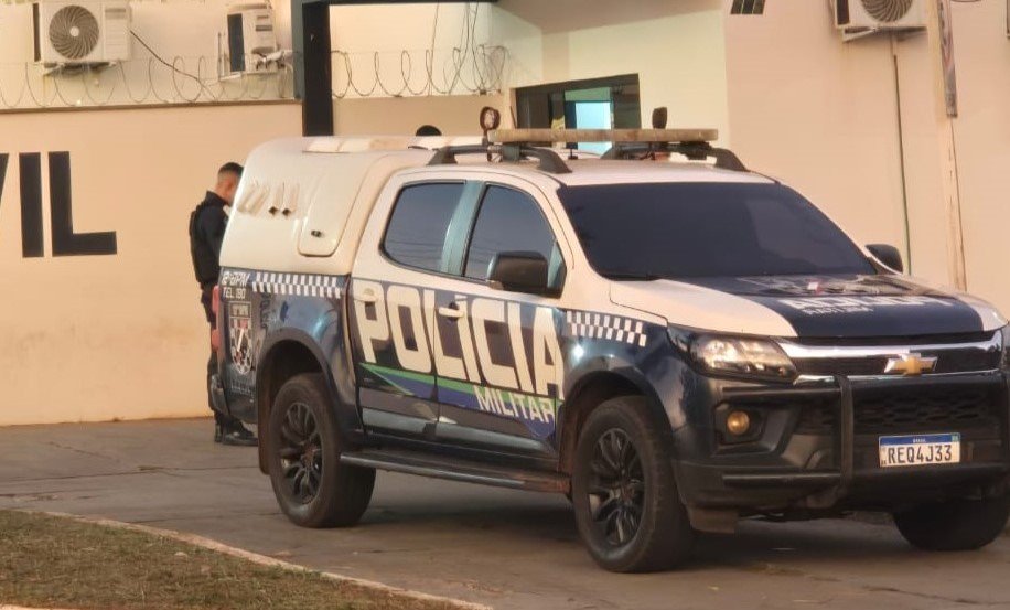 Viatura da Polícia Militar estacionada em frente a um prédio.
