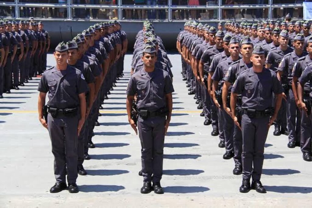 Policiais militares em formação perfilados em um pátio externo.