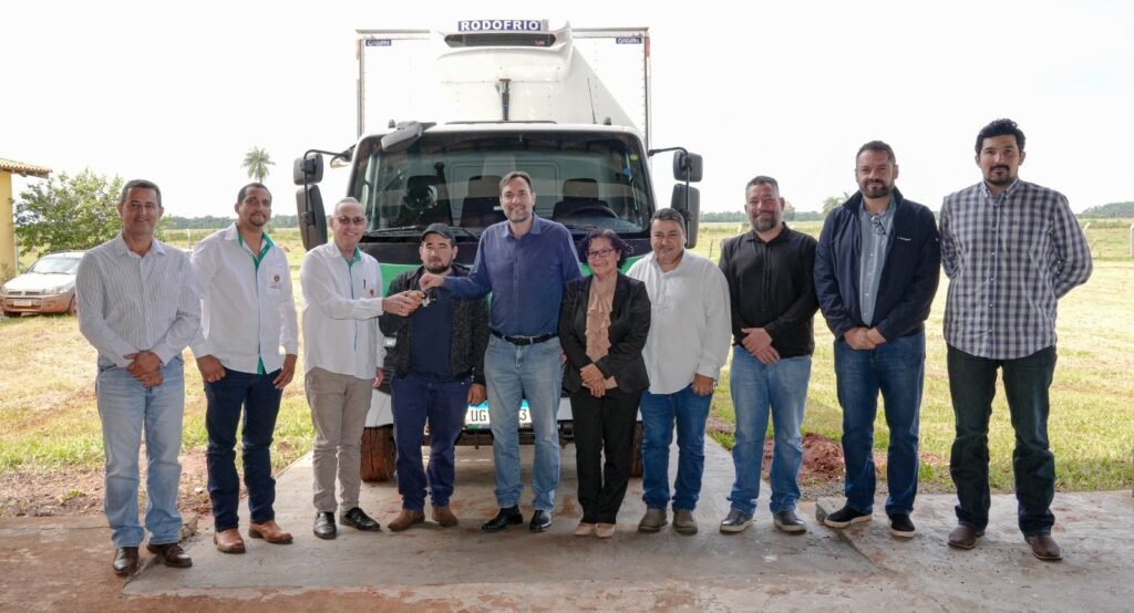 Grupo de pessoas posando em frente a um caminhão frigorífico.