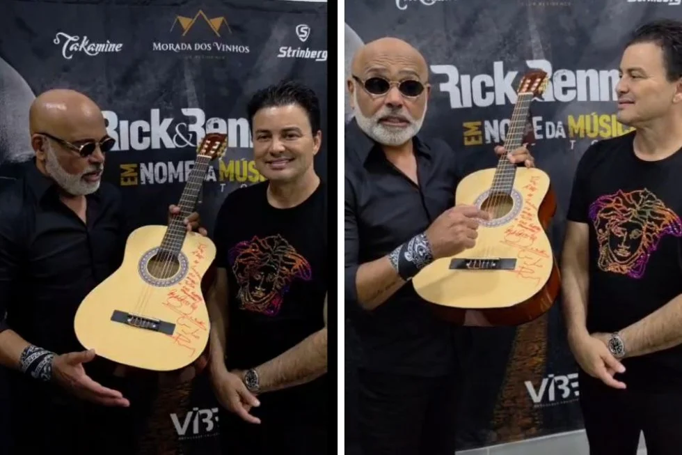Rick e Renner segurando um violão autografado em um evento.