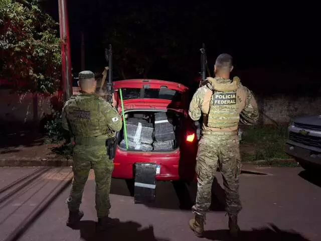 Polícia Federal apreende pacotes em porta-malas de carro vermelho.