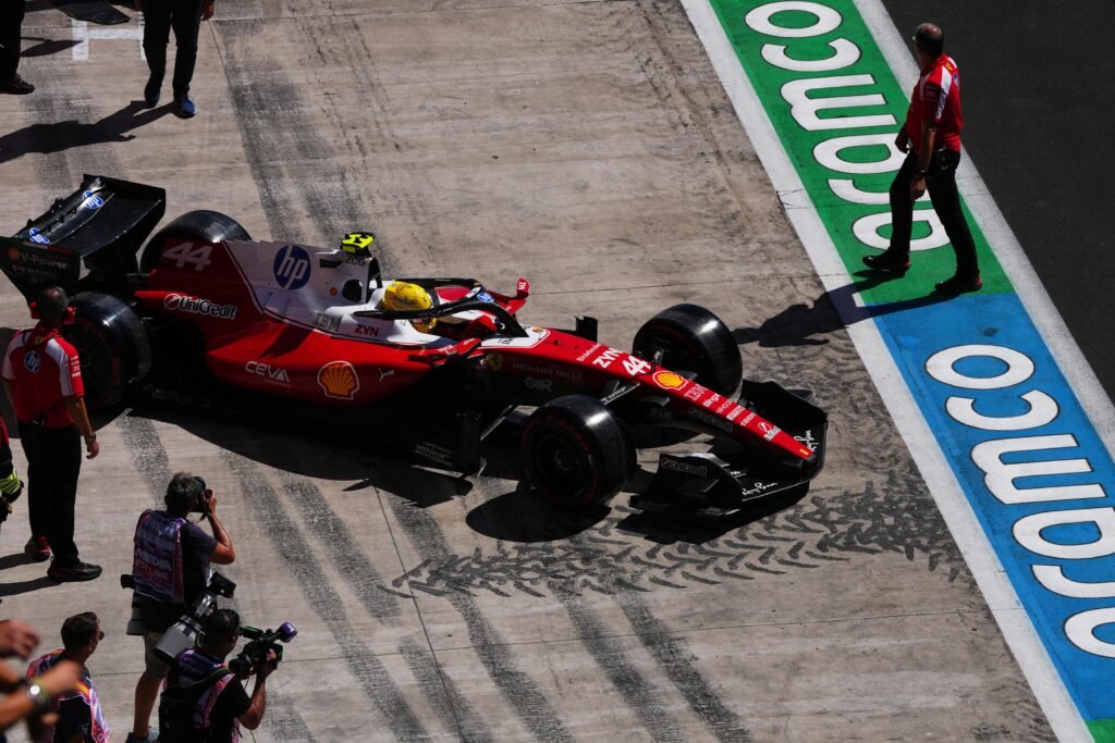 Carro Ferrari F1 número 44 no pit lane com fotógrafos.