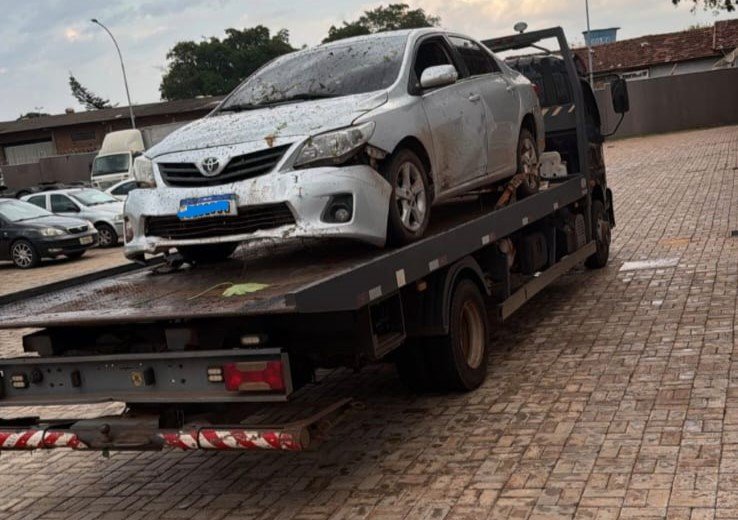 Toyota Corolla branco danificado em cima de um caminhão guincho.