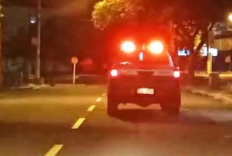Viatura policial com luzes vermelhas acesas em rua escura.
