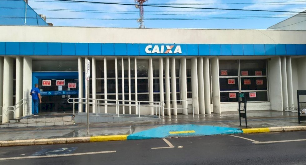 Fachada de agência da Caixa Econômica Federal com cartazes de greve.