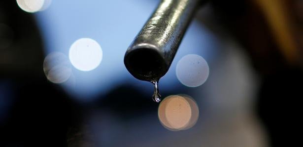 Bico de bomba de combustível com gota de líquido pendurada.