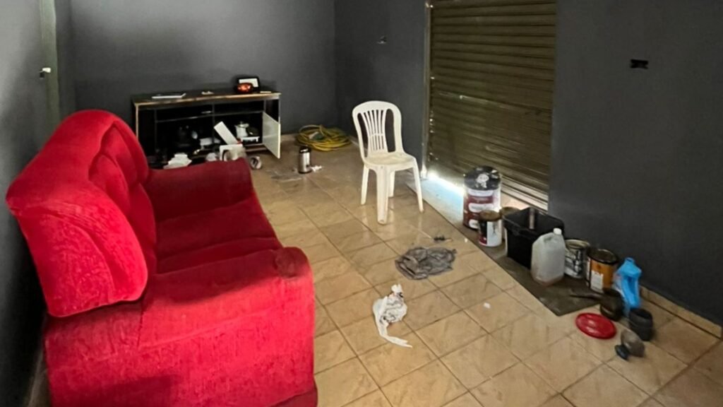 Interior de sala com sofá vermelho e materiais de pintura.