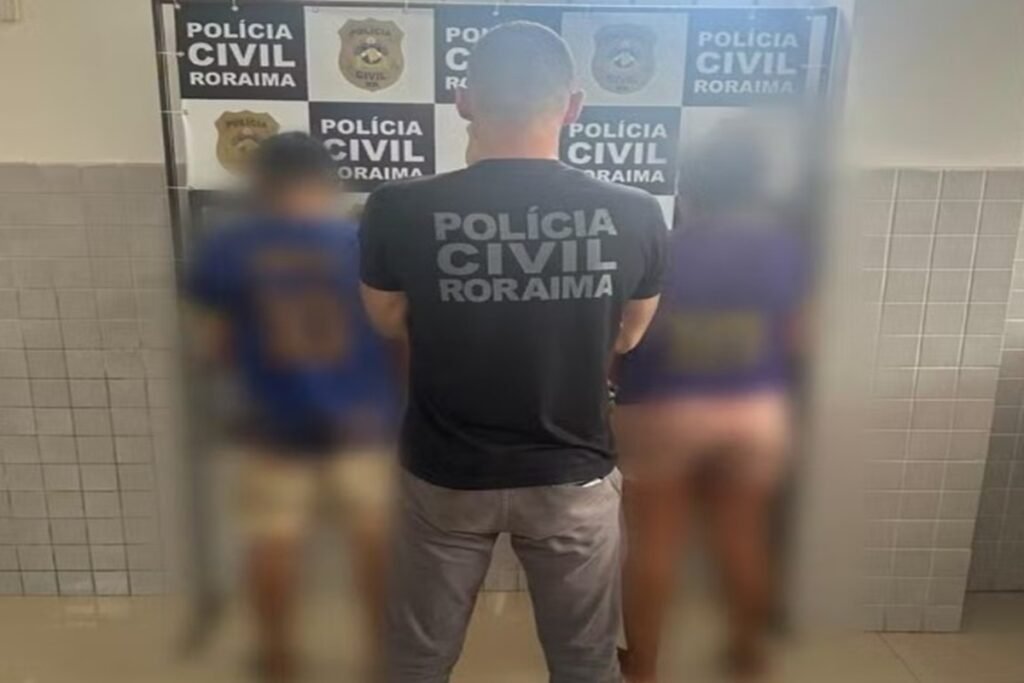 Policial civil de Roraima de costas entre duas pessoas desfocadas.