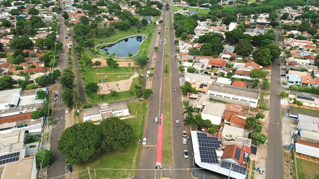 Vista aérea de avenida com ciclovia, parque e casas.