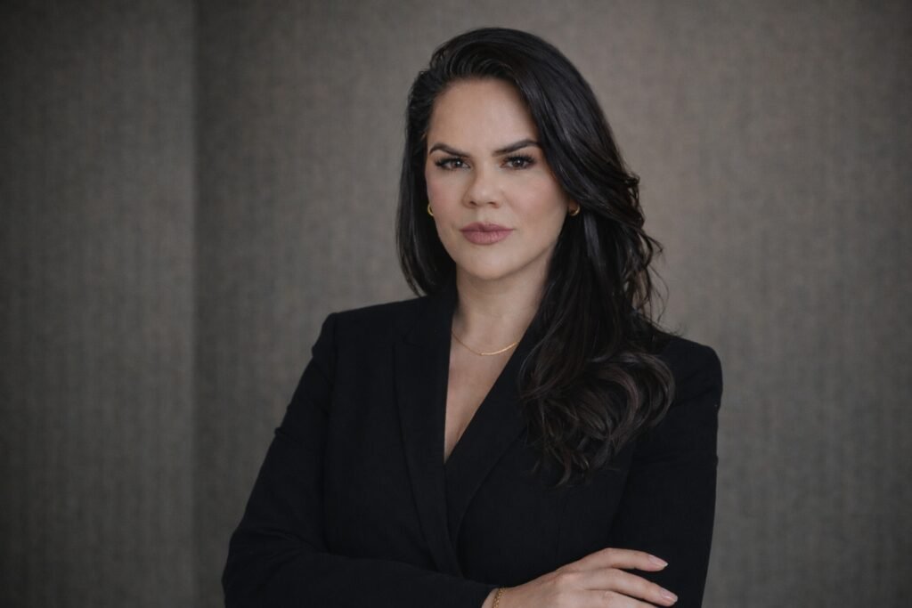 Mulher profissional de blazer preto com braços cruzados.