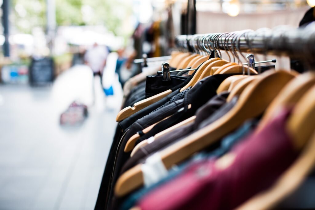 Arara de roupas com cabides de madeira em mercado externo.