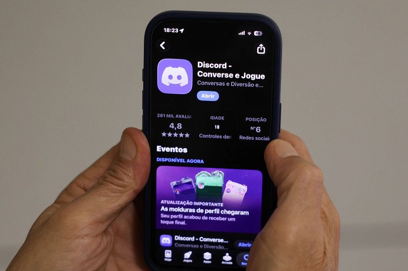 Mãos segurando celular exibindo o aplicativo Discord na loja.