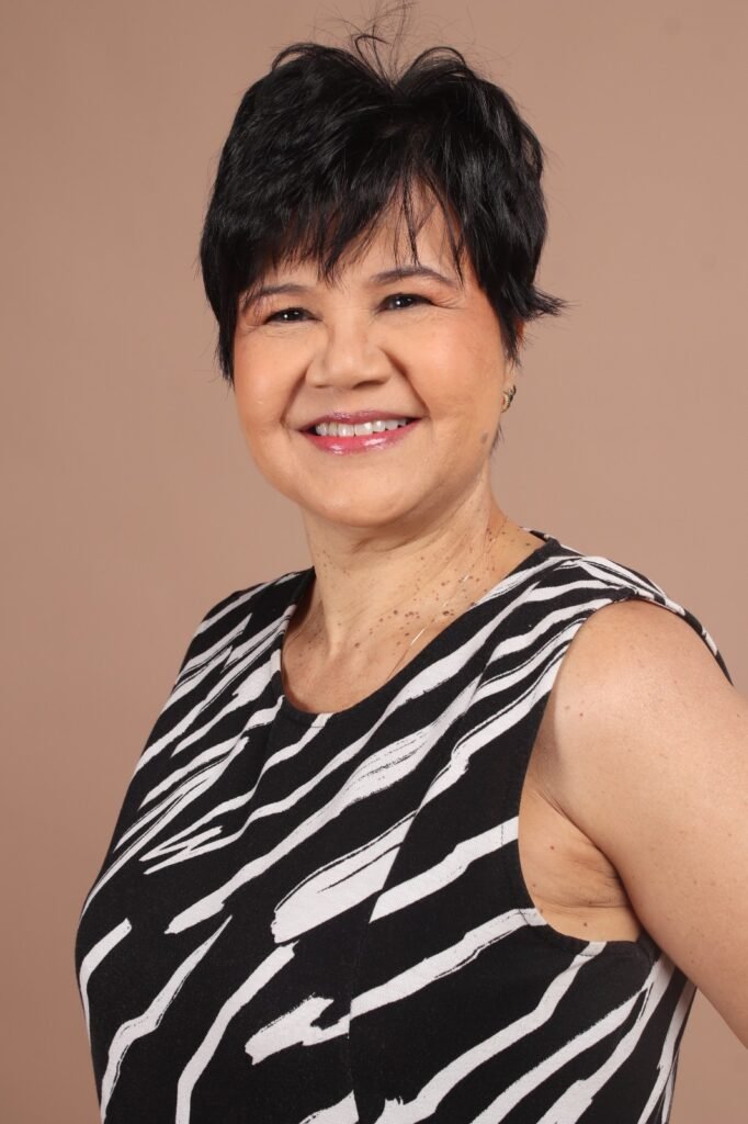 Mulher sorridente com cabelo curto preto e blusa estampada.