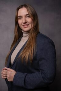 Mulher sorridente com blazer azul e cabelo longo castanho.