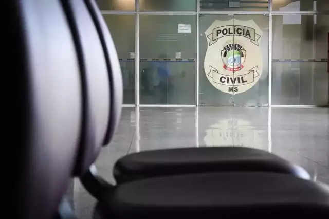 Logotipo da Polícia Civil de MS em porta de vidro.