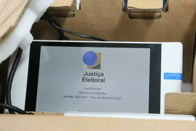 Tela de urna eletrônica brasileira inicializando dentro de uma caixa.