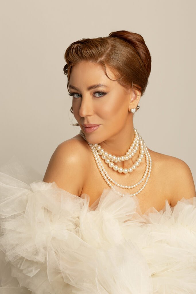 Mulher elegante com colar de pérolas e cabelo estilo vintage.