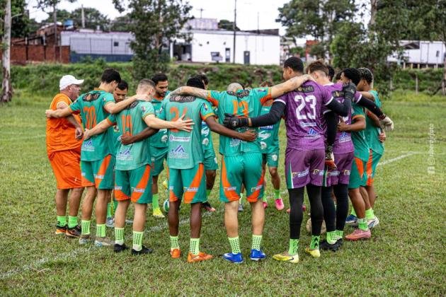 Time de futebol reunido em círculo no gramado.