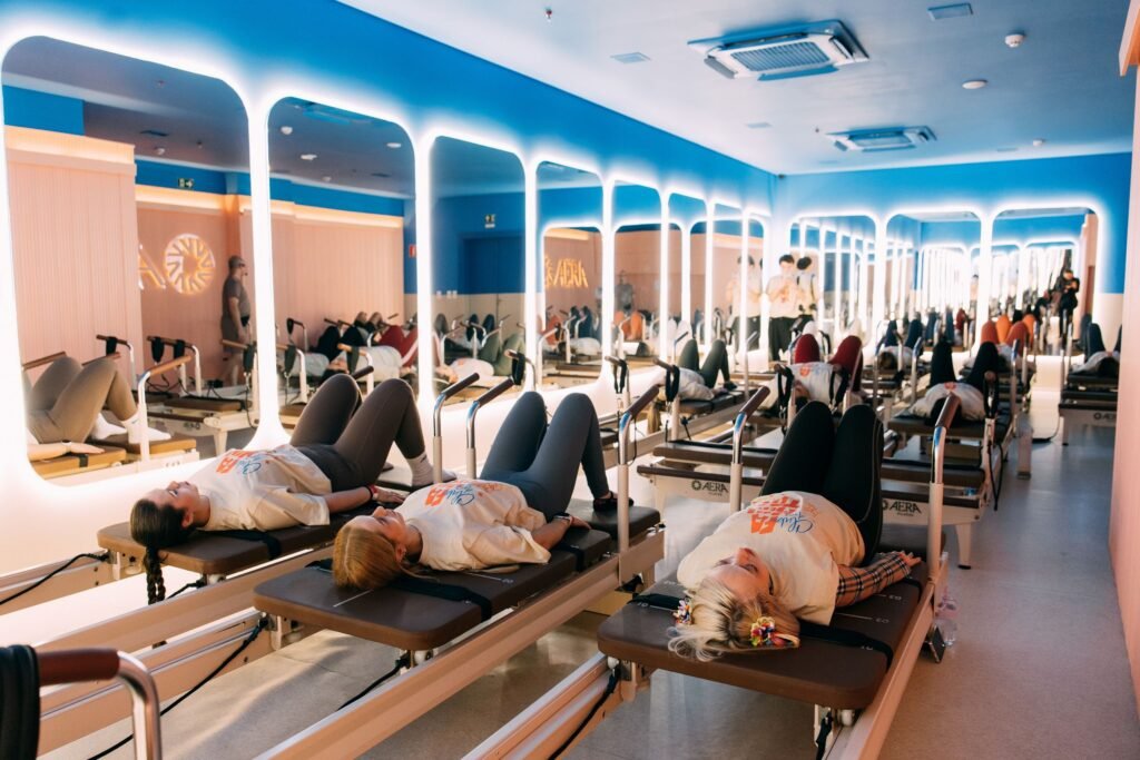 Mulheres praticando pilates em aparelhos reformer em estúdio moderno.