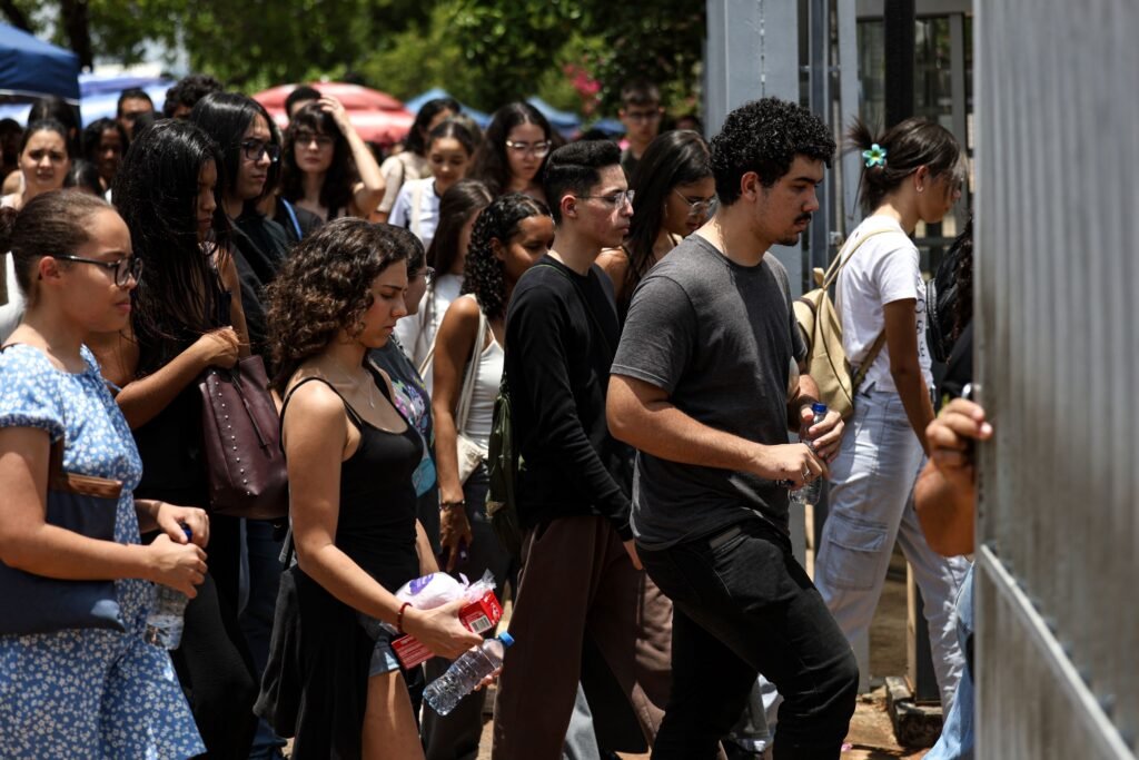 Estudantes entram em local de prova carregando água e lanches.
