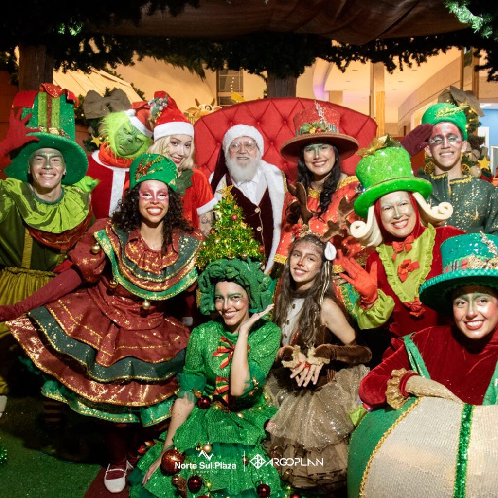 Papai Noel e personagens natalinos posando para foto em shopping.