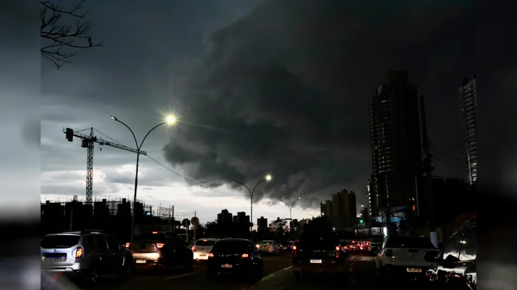 Nuvem de tempestade escura sobre trânsito urbano ao anoitecer.