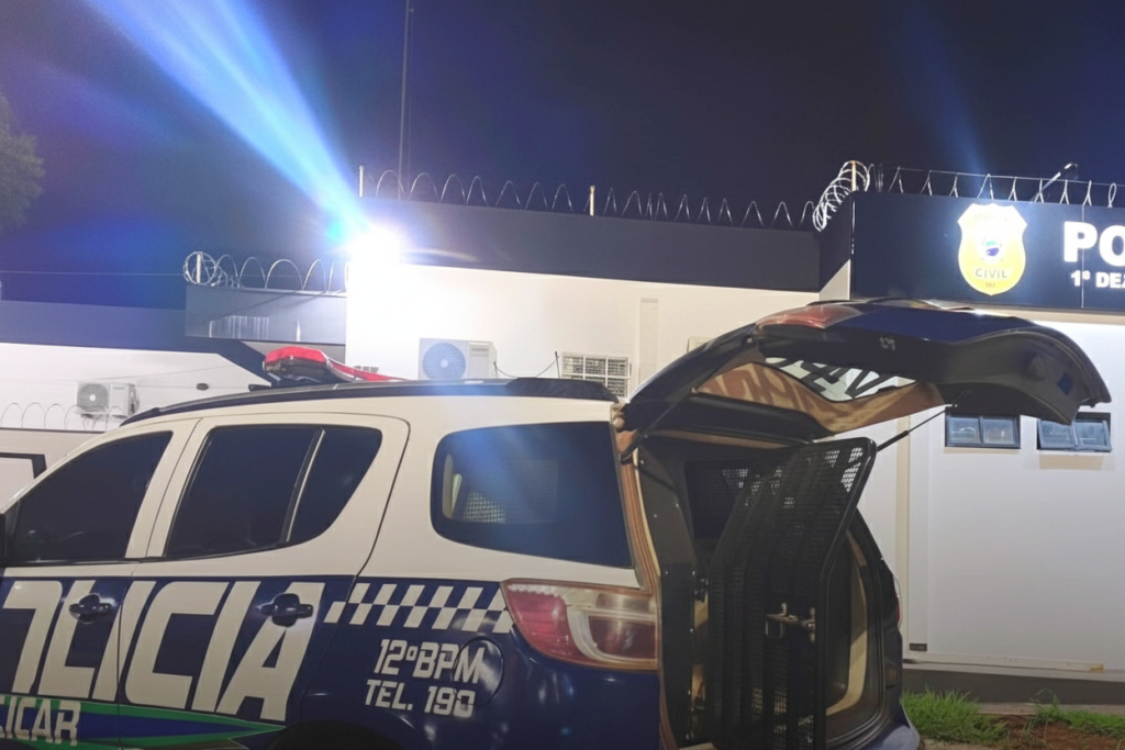 Viatura da polícia com porta-malas aberto em frente à delegacia.