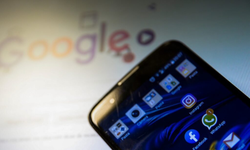 Smartphone com ícones de aplicativos e logotipo do Google ao fundo.