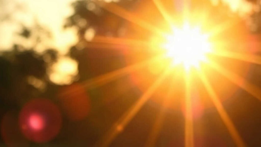 Sol brilhante com raios de luz e fundo desfocado.