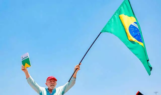 Lula segura a bandeira do Brasil e a Constituição Federal.