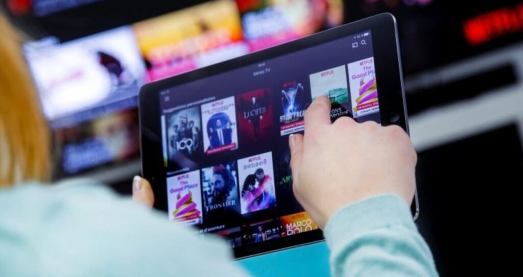 Pessoa segurando tablet com o aplicativo da Netflix aberto.