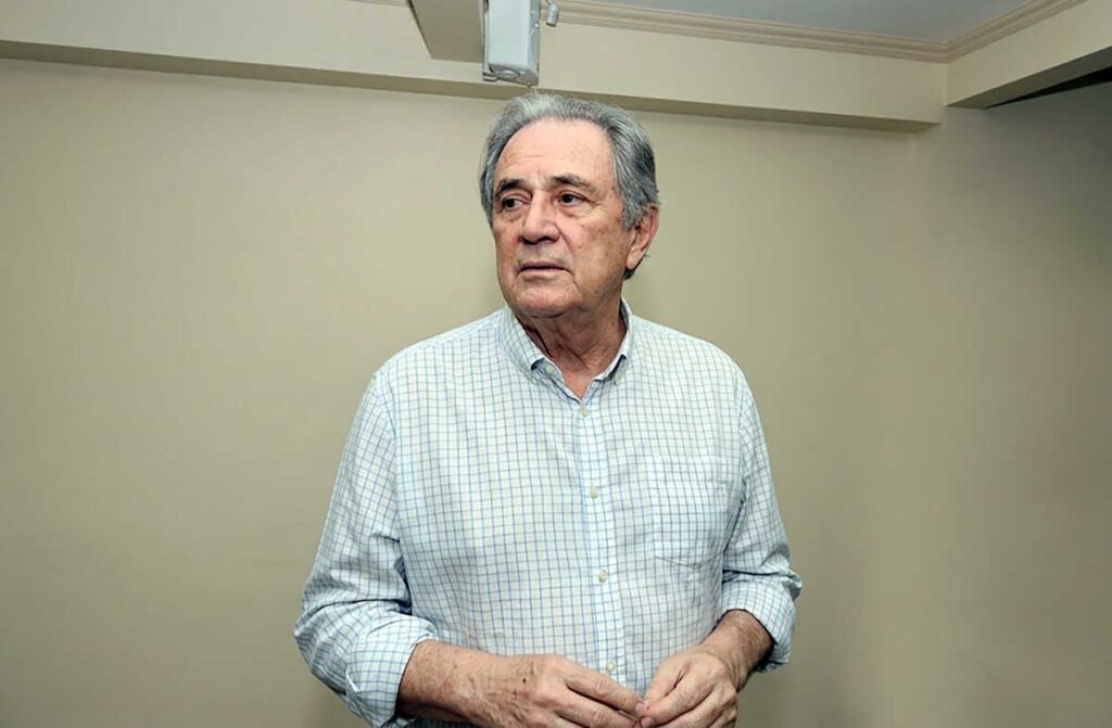 Homem idoso de camisa xadrez clara olhando para o lado.