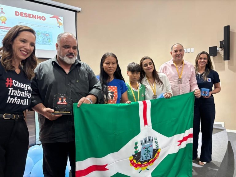 Grupo de pessoas segurando bandeira de Naviraí em premiação.