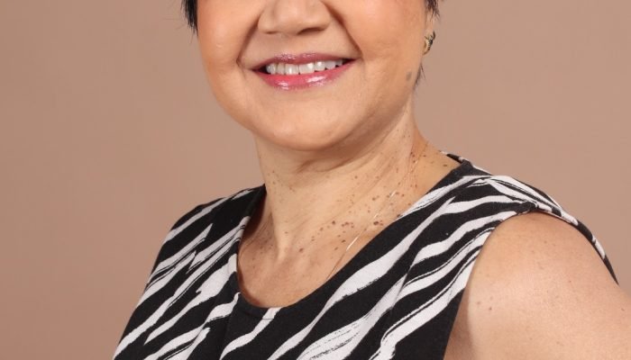 Mulher sorridente com cabelo curto preto e blusa estampada.