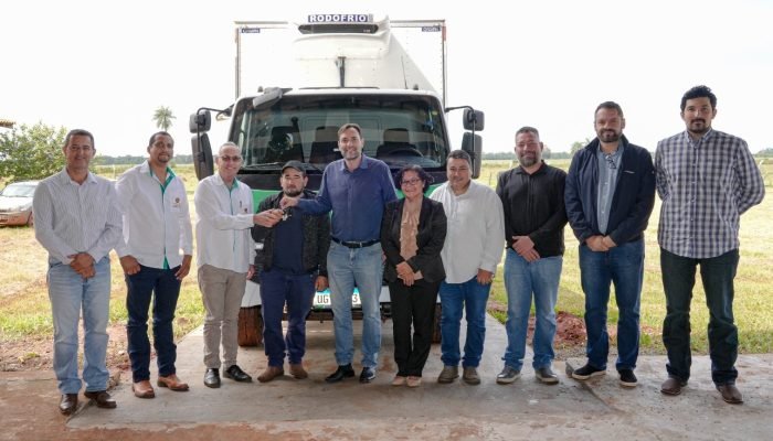 Grupo de pessoas posando em frente a um caminhão frigorífico.