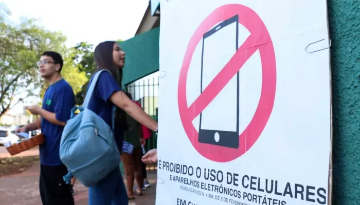 Na frente da escola, o cartaz é o lembrete da nova restrição em sala de aula (Foto: Henrique Kawaminami)