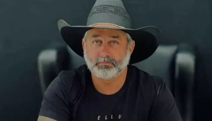 Homem de barba grisalha usando chapéu de cowboy preto.