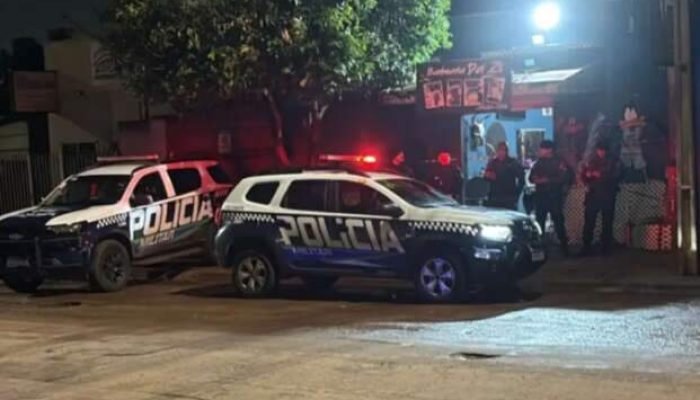 Duas viaturas da Polícia Militar estacionadas em rua à noite.