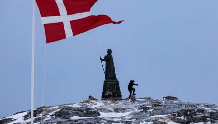 Bandeira da Dinamarca tremula ao lado da estátua de Hans Egede em Nuuk, Groenlân
