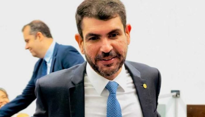 Político Marangoni de terno e gravata azul sorrindo em evento.