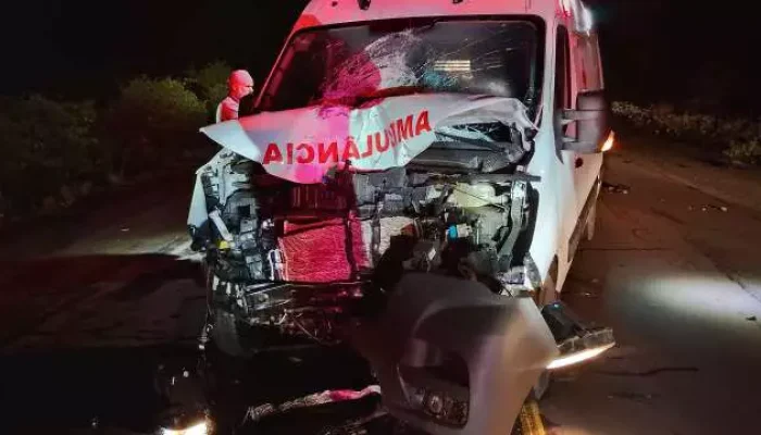 Ambulância branca com a frente totalmente destruída após colisão severa.