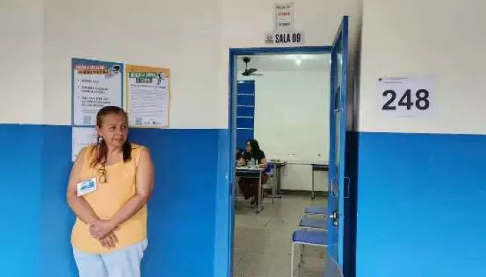 Mulher em frente a uma sala de aula identificada.