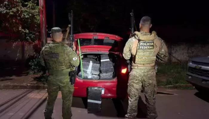 Polícia Federal apreende pacotes em porta-malas de carro vermelho.