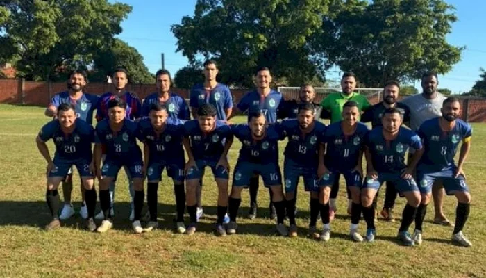 Time de futebol amador posando para foto no campo.