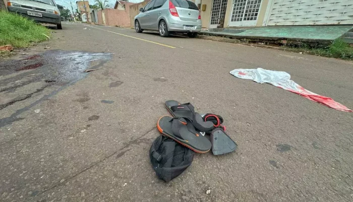 Mancha da sangue no asfalto e objetos da vítima no local onde crime aconteceu (Foto: Marcos Maluf)