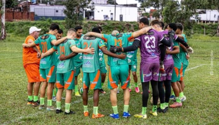 Time de futebol reunido em círculo no gramado.