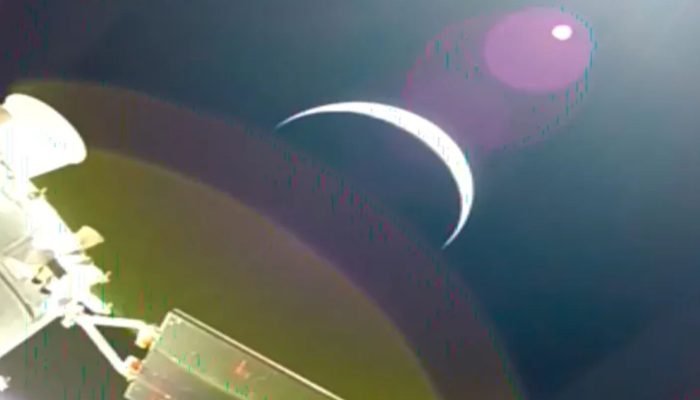 O crescente da Terra é visto através de uma câmera no painel solar da espaçonave